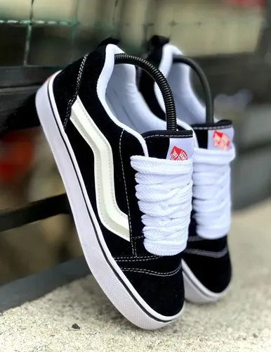 Black sneakers with white laces hanging on a railing, close-up view