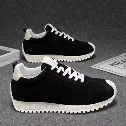Black sneakers with white laces and chunky off-white soles on a gray background