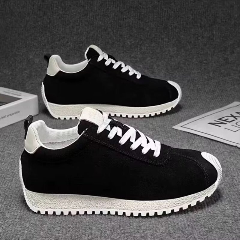 Black sneakers with white laces and chunky off-white soles on a gray background