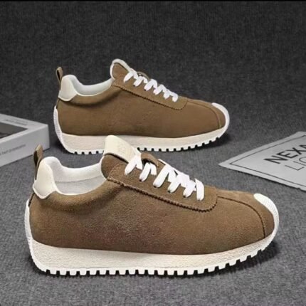 Brown suede sneakers with white laces and thick white soles on a gray surface