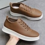 Brown leather sneakers with white chunky sole on gray surface, casual footwear for daily wear.