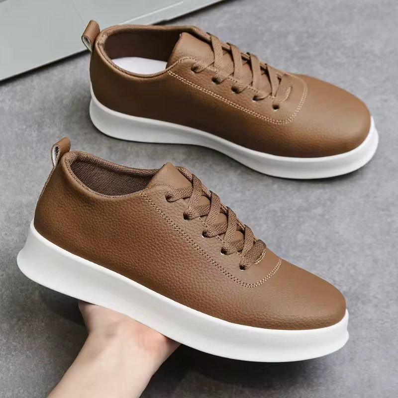 Baskets cuir marron homme élégantes confort quotidien Brown leather sneakers with white chunky sole on gray surface, casual footwear for daily wear.